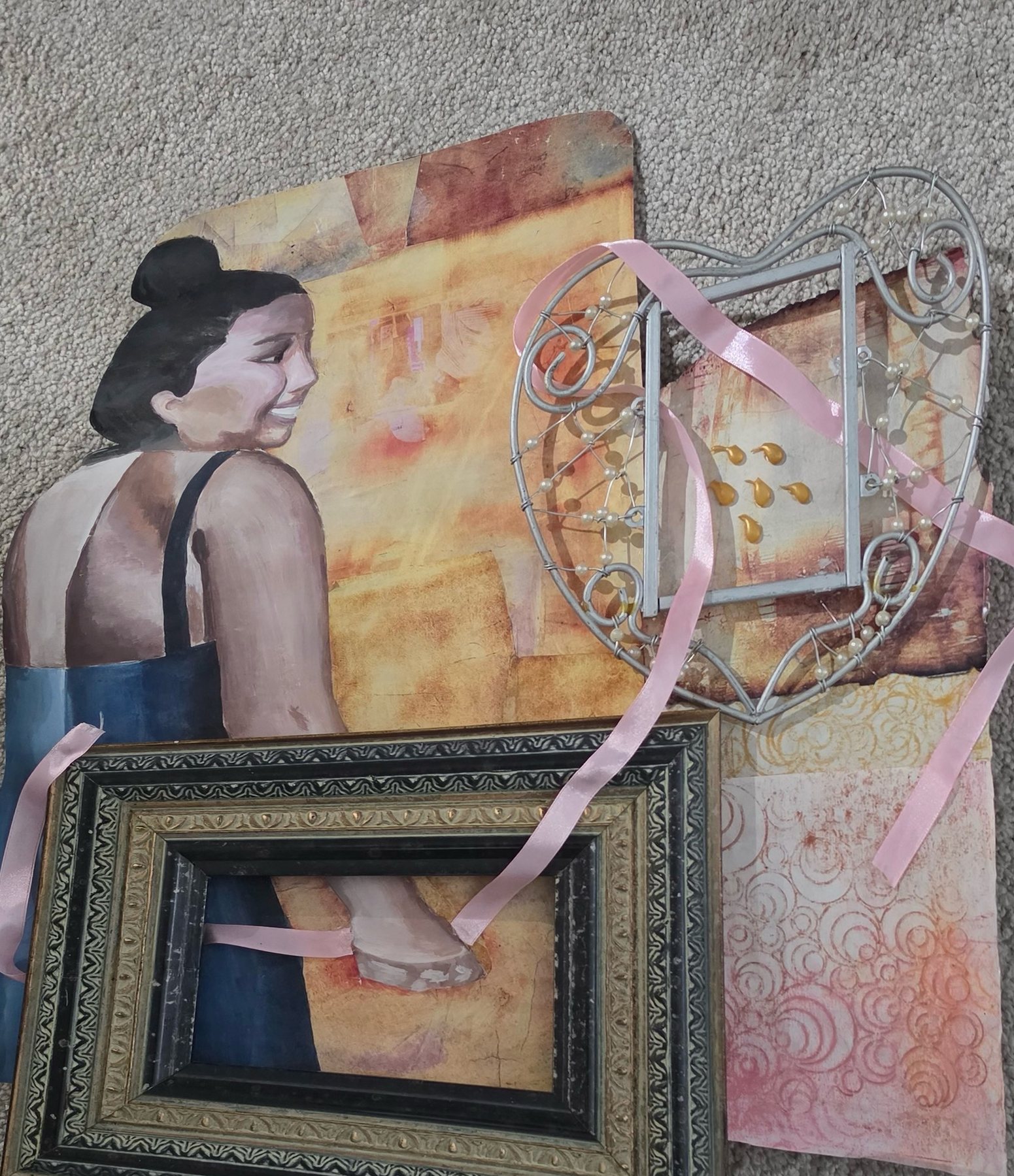 Mixed media piece: a painted cut-out of a dancer with a hair bun, combined with an ornate frame, wire basket, ribbon, and textured papers.